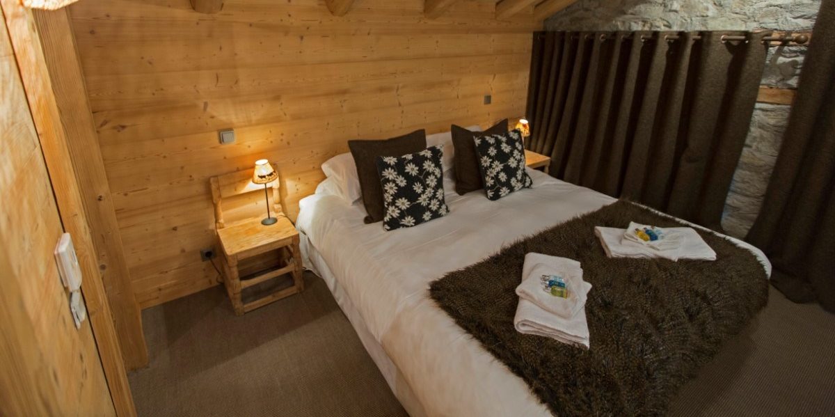 Chalet La Petite Ferme Val d'Isere Tignes & Val d'Isere Frankrijk wintersport skivakantie luxe slaapkamer 2-persoonsbed handdoeken lamp schuin dak houten balken