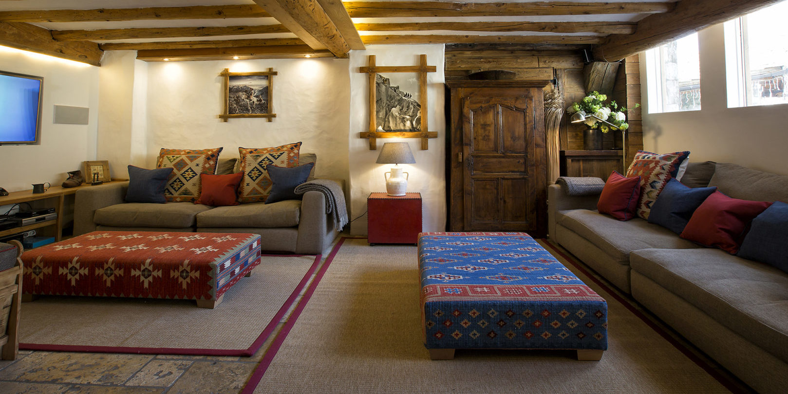 Chalet Lafitenia Val d'Isere Tignes-Val d'Isere Frankrijk wintersport skivakantie luxe TV kamer lounge banken hockers gekleurde kussens flatscreen vloerkleed houten balken