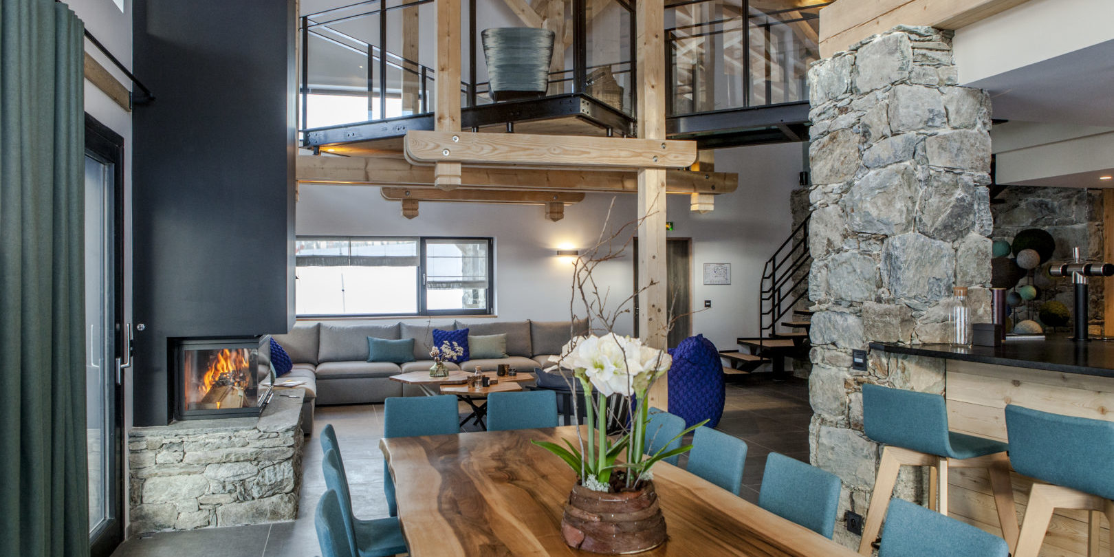CLUB 21Forty Arc 2000 Paradiski Frankrijk wintersport skivakantie luxe eetkamer grote eettafel blauwe stoelen plant open haard hoekbank mezzanine trap keuken ramen
