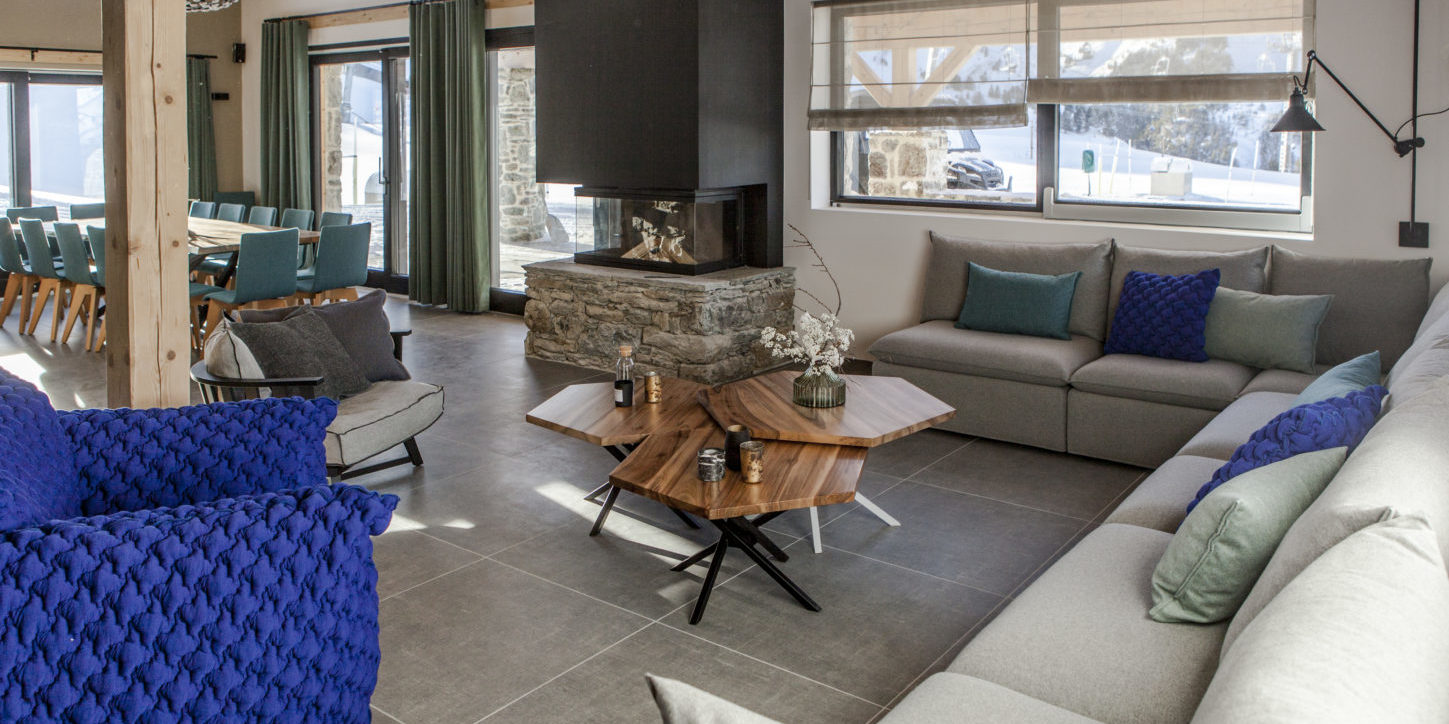 CLUB 21Forty Arc 2000 Paradiski Frankrijk wintersport skivakantie luxe living hoekbank kussens blauwe fauteuil salontafels kaarsen open haard eetkamer hanglamp ramen