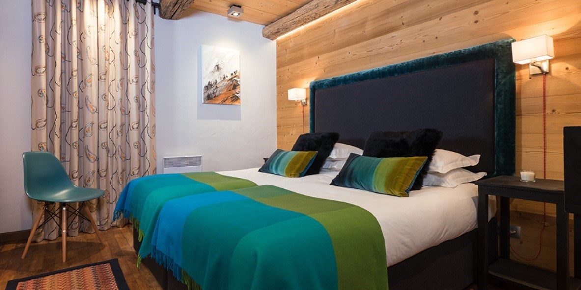 Club Bellevarde Lodge Val d'Isere Tignes & Val d'Isere Frankrijk wintersport skivakantie luxe slaapkamer aparte bedden blauwe stoel vloerkleed houten balken