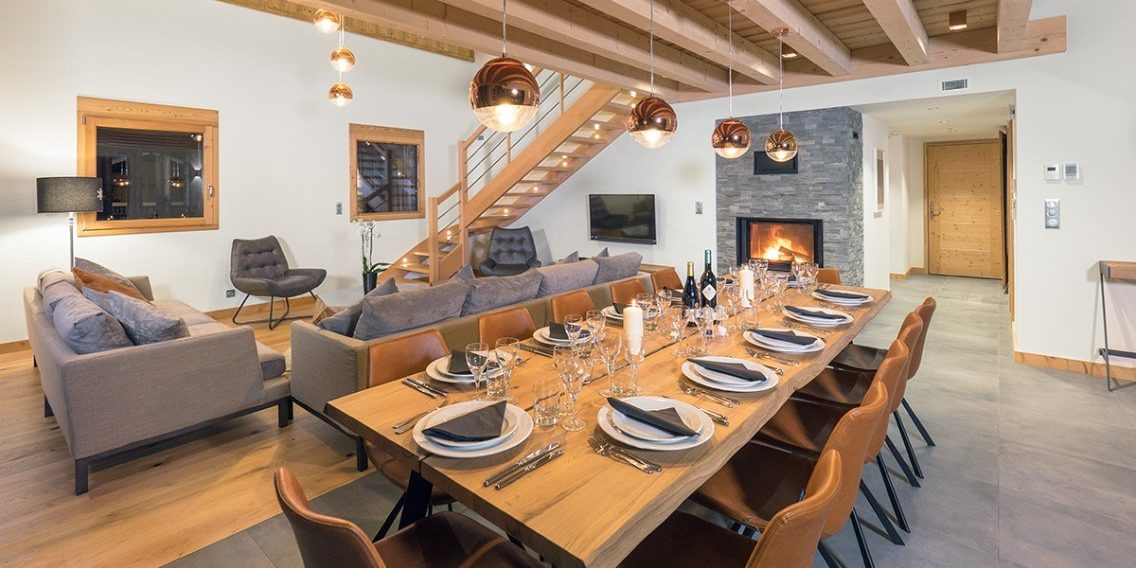 Colibri Penthouse Morzine Les Portes du Soleil Frankrijk wintersport skivakantie luxe eetkamer gedekte tafel kaars wijn wijnglazen hanglampen open haard houten balken