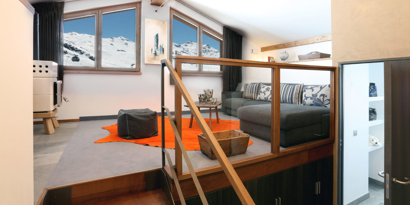 Hotel Pashmina Le Refuge Val Thorens Les 3 Vallees Frankrijk wintersport skivakantie luxe Suite Prestige XXL zitkamer hoekbank hockers oranje vloerkleed houtkachel ramen trap