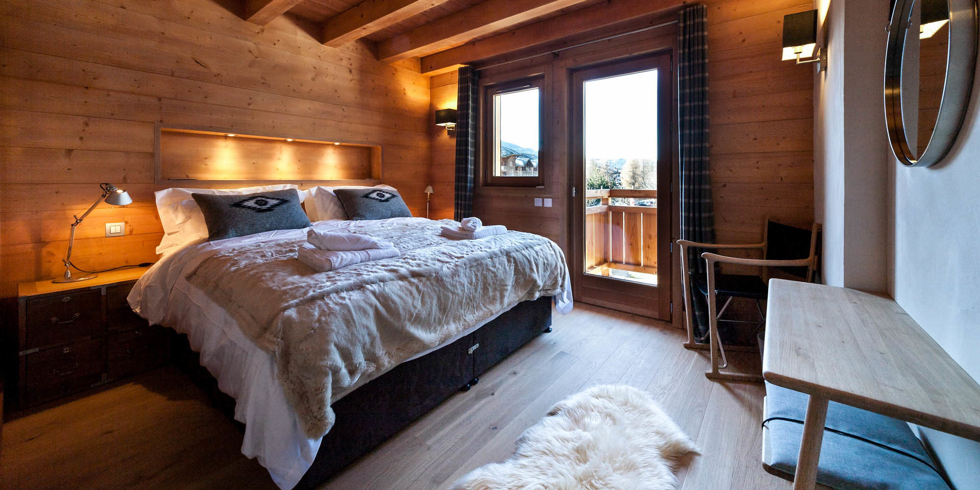 Penthouse Les Gets Les Portes du Soleil Frankrijk wintersport skivakantie luxe slaapkamer 2-persoonsbed vloerkleed stoel spiegel raam houten balken