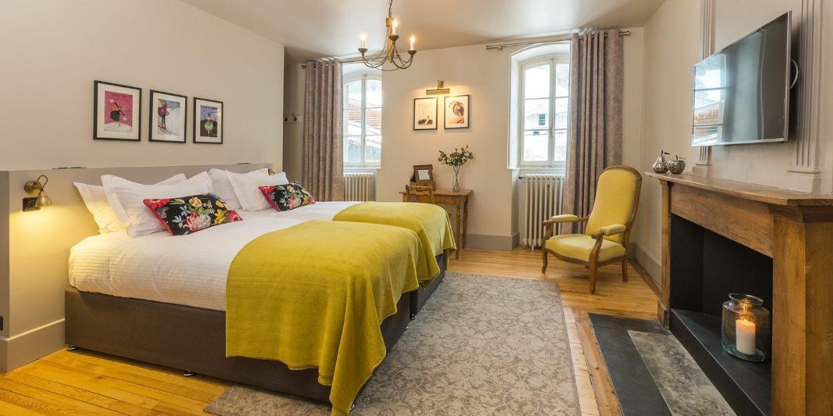 The Manoir Morzine Les Portes du Soleil Frankrijk wintersport skivakantie luxe slaapkamer aparte bedden fauteuil kaars TV schilderijen hanglamp raam